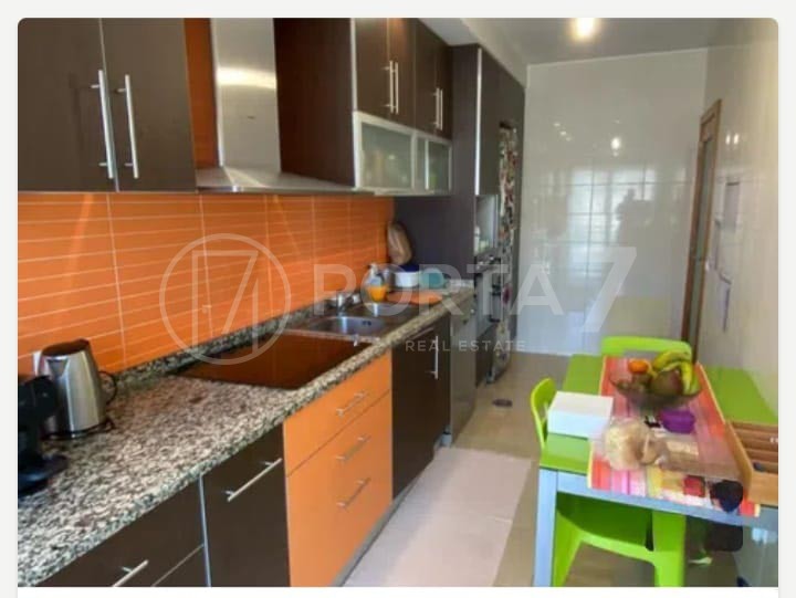 Cozinha equipada com fogão, microondas, placa e frigorífico e uma mesa pequena