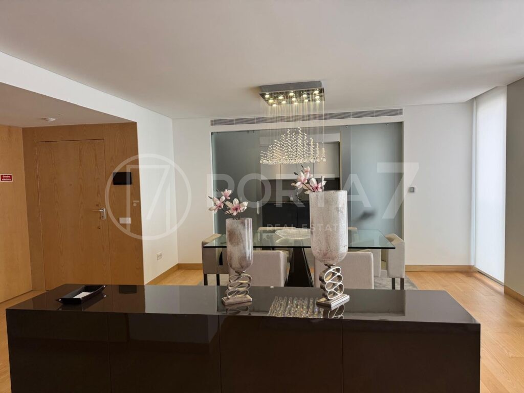 Sala de jantar com móvel preto que separa a sal de estar e de jantar e de onde é possível ver a porta de entrada do apartamento