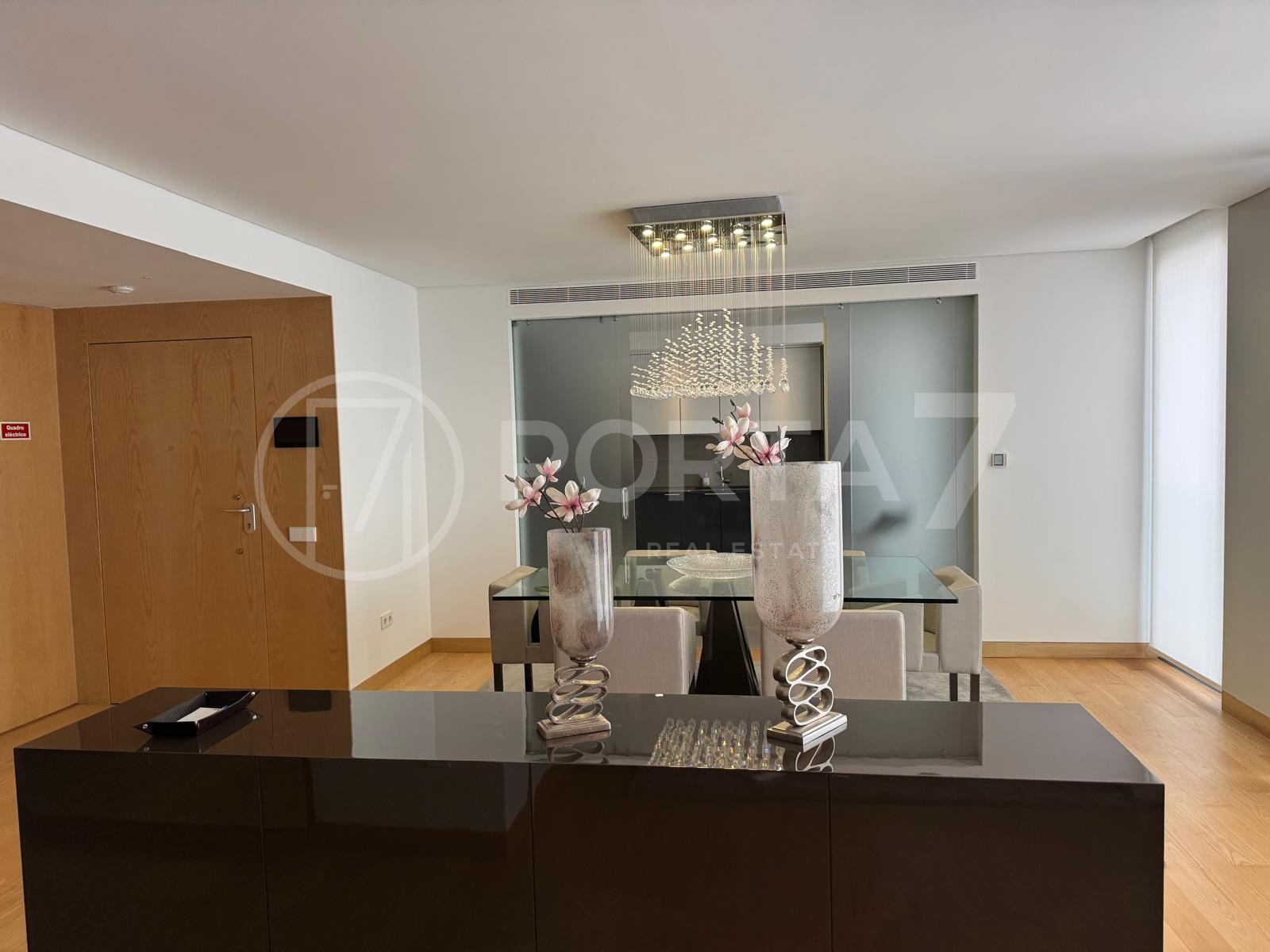 Sala de jantar com móvel preto que separa a sal de estar e de jantar e de onde é possível ver a porta de entrada do apartamento